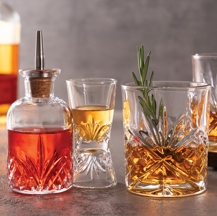 A refined four-piece whiskey and rye set featuring crystal-cut Dublin glassware, styled on a wood bar with warm amber tones — perfect for bourbon lovers and elegant entertaining.