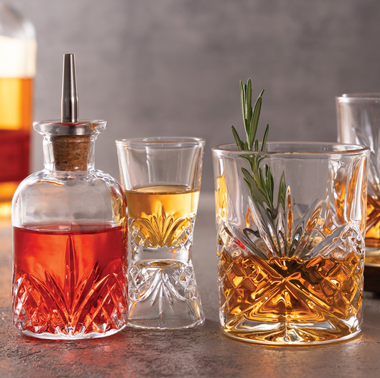 A refined four-piece whiskey and rye set featuring crystal-cut Dublin glassware, styled on a wood bar with warm amber tones — perfect for bourbon lovers and elegant entertaining.